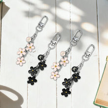 Load image into Gallery viewer, Two keychains with floral charms on a light wooden surface.
